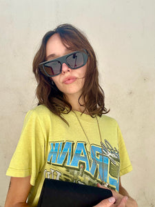 Person wearing a yellow t-shirt with text and sunglasses against a plain background