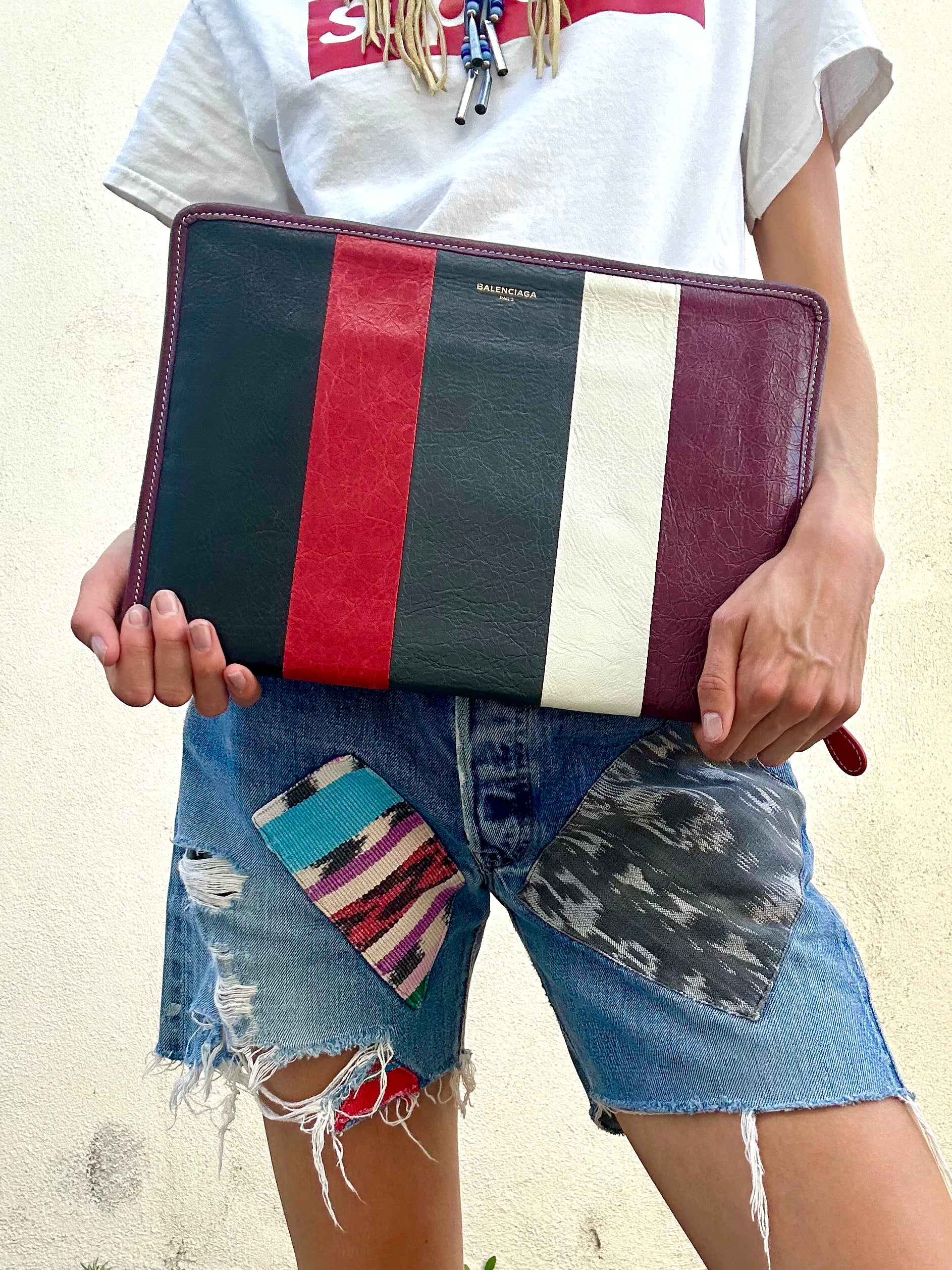 Person holding a multicolored clutch bag with a neutral background