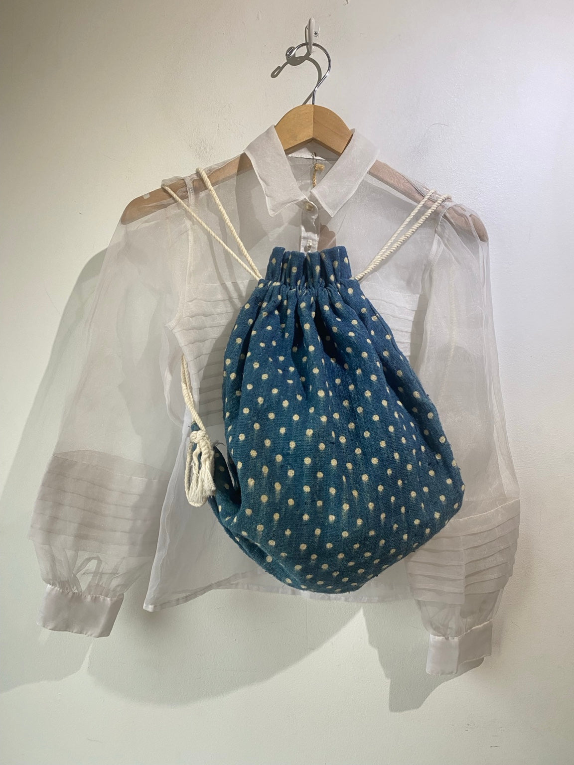Lineage Botanica indigo dotted drawstring backpack, styled on a white blouse