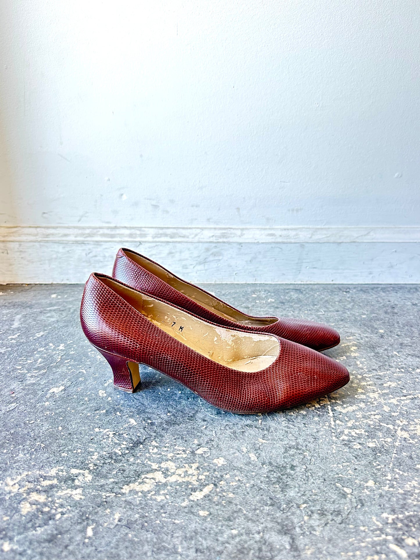 Pair of red high-heeled shoes on a gray surface with a white background