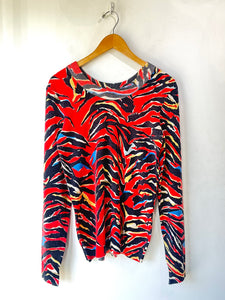 Colorful zebra print sweater on a wooden hanger against a white background