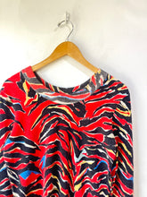 Colorful patterned top on a wooden hanger against a white background