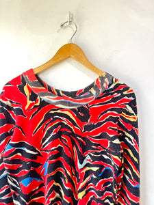 Colorful patterned top on a wooden hanger against a white background
