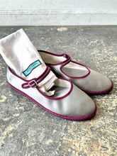 Pair of gray shoes with purple trim on a textured surface