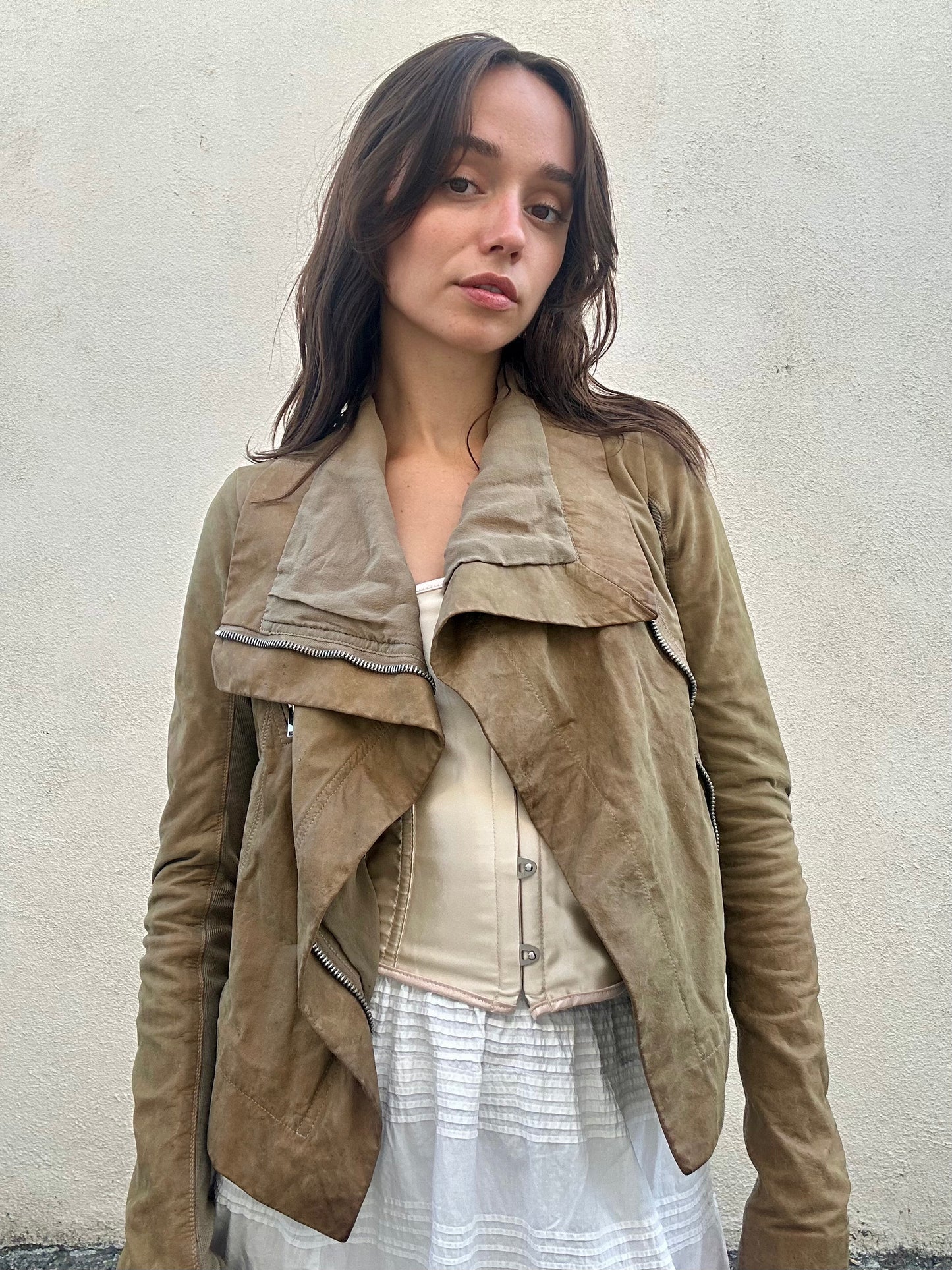 Woman wearing a brown suede jacket against a plain background
